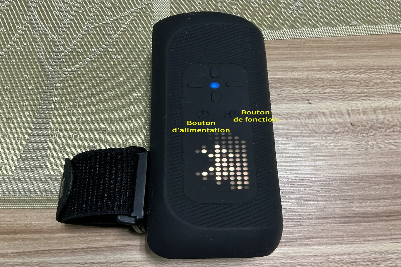 The Handy 2 Pro allumé avec un voyant bleu, posé sur une table avec sa sangle de fixation.