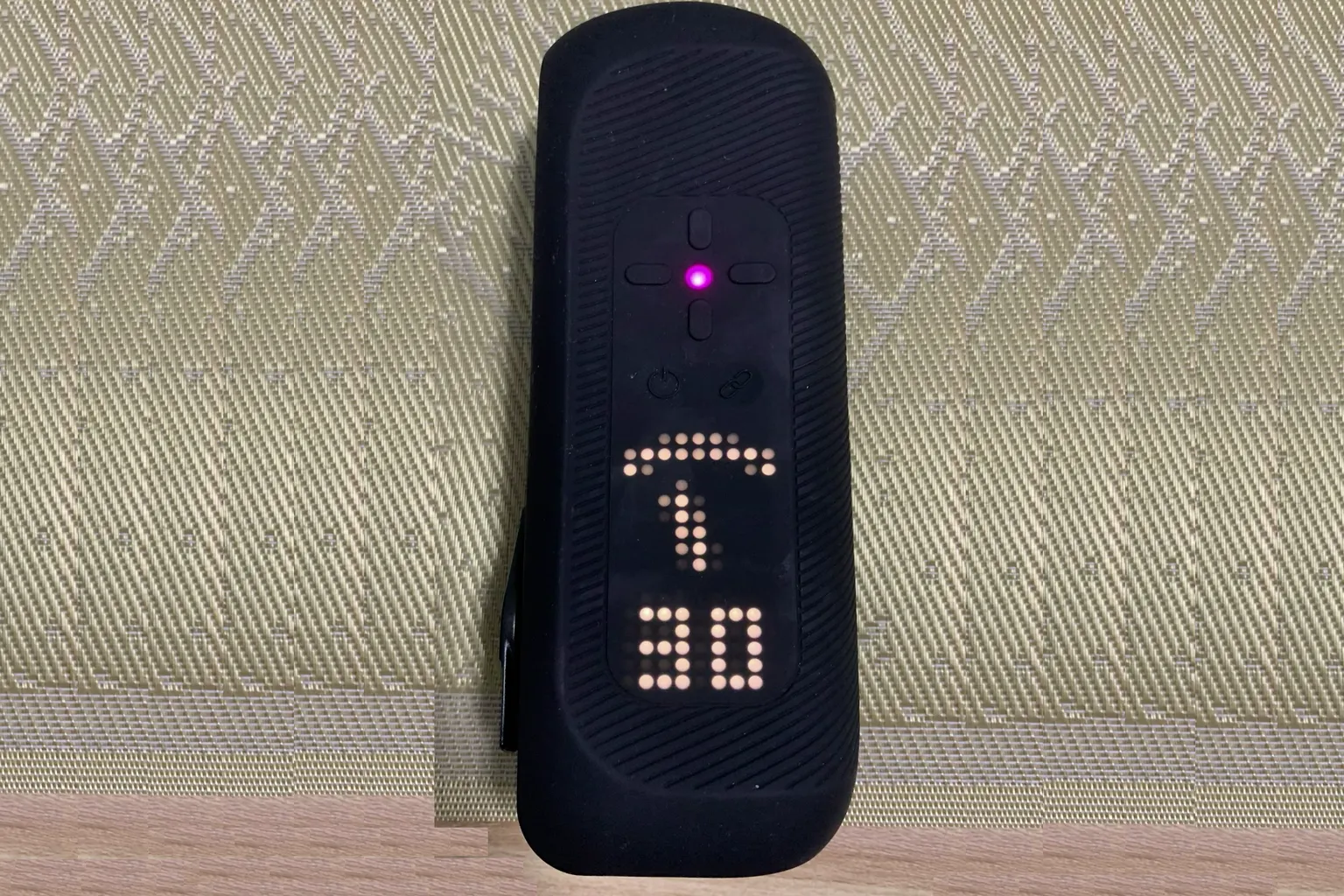 The Handy 2 Pro display showing the action intensity set to 80, with an upward arrow icon and a pink indicator light.