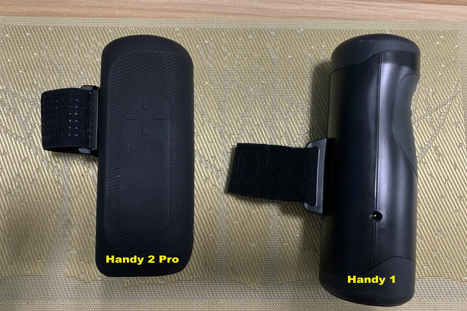 Side-profile comparison of The Handy 2 Pro and original Handy, showing differences in body shape and grip strap design.